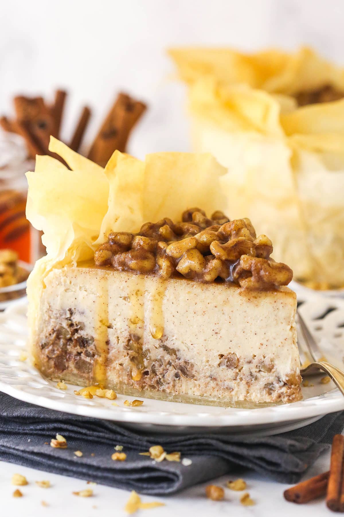 With a phyllo dough crust, creamy cheesecake filling, and honey walnut topping, Baklava Cheesecake is a fun twist on the traditional dessert. A slice of baklava cheesecake on a white plate