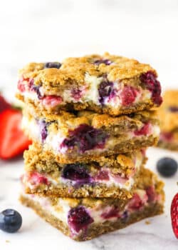 A stack of berry oatmeal cheesecake bars. The top one has a bite taken out of it.