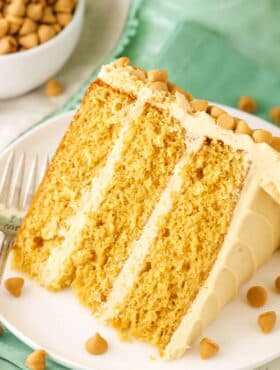 A slice of Ultimate Butterscotch Cake next to a fork on a white plate