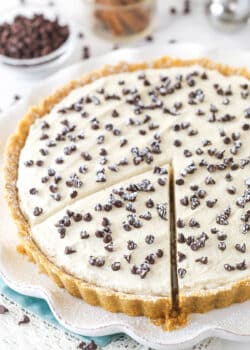 Cannoli tart on a serving platter with a slice cut and ready to serve.
