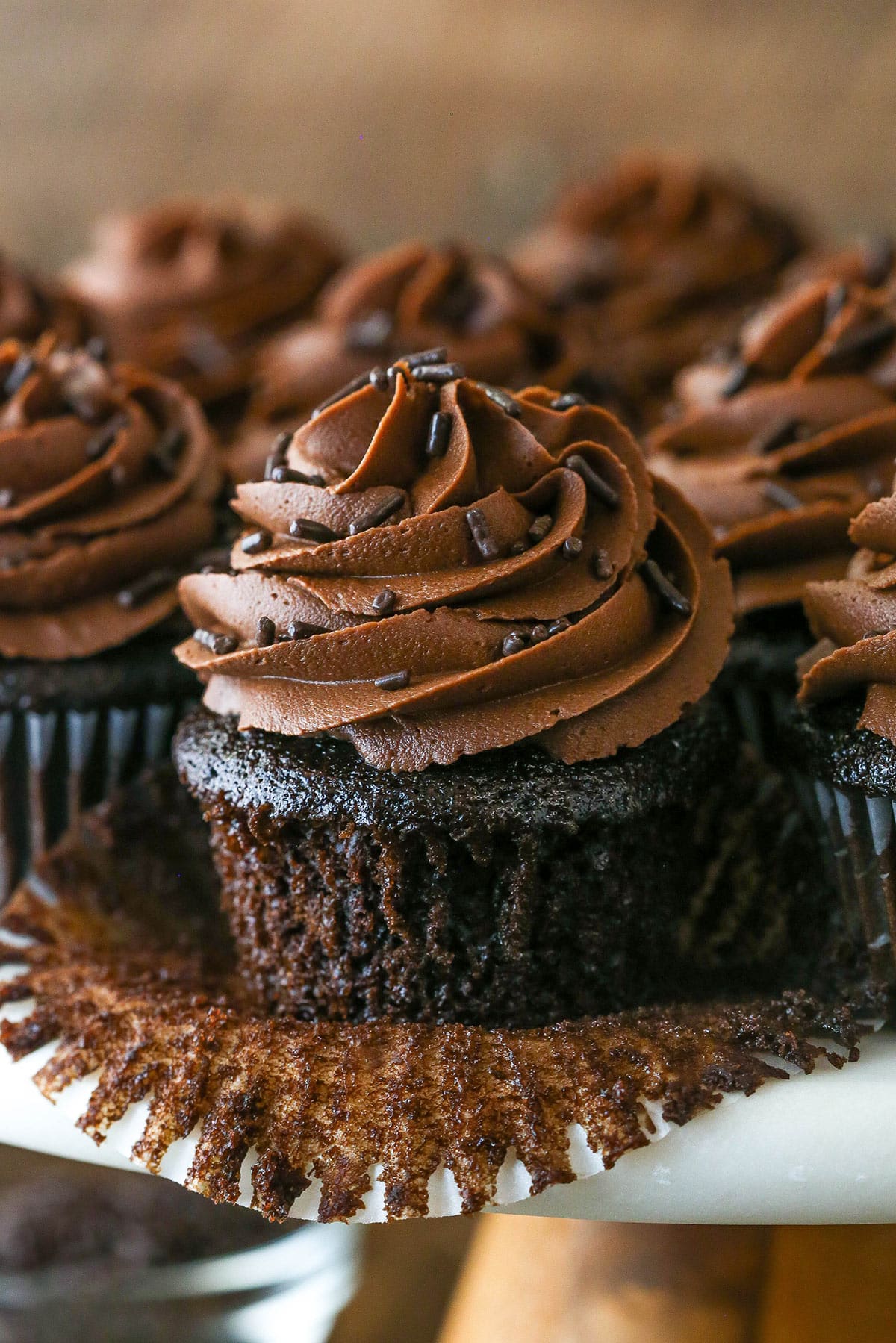 These moist chocolate cupcakes are full of rich chocolate flavor. They are so moist and covered in silky frosting made from real chocolate. Pealing back the cupcake liner on a moist chocolate cupcake.