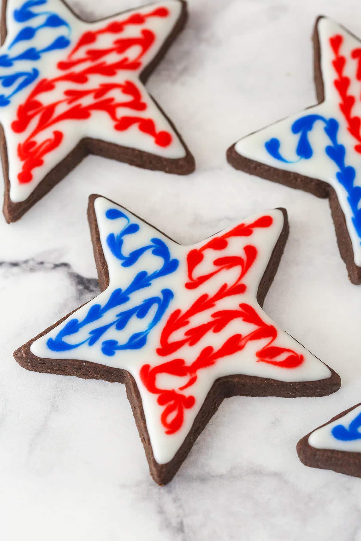 Perfectly soft and chewy, Chocolate Cut Out Cookies are easy cookies that the whole family will love. Decorate with your favorite icing. Chocolate cutout cookies decorated with red white and blue icing