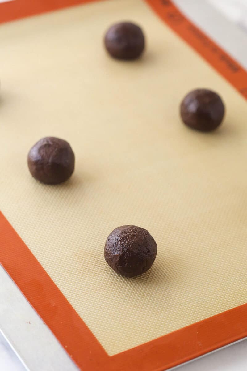 Balls of chocolate cookie dough on a baking sheet
