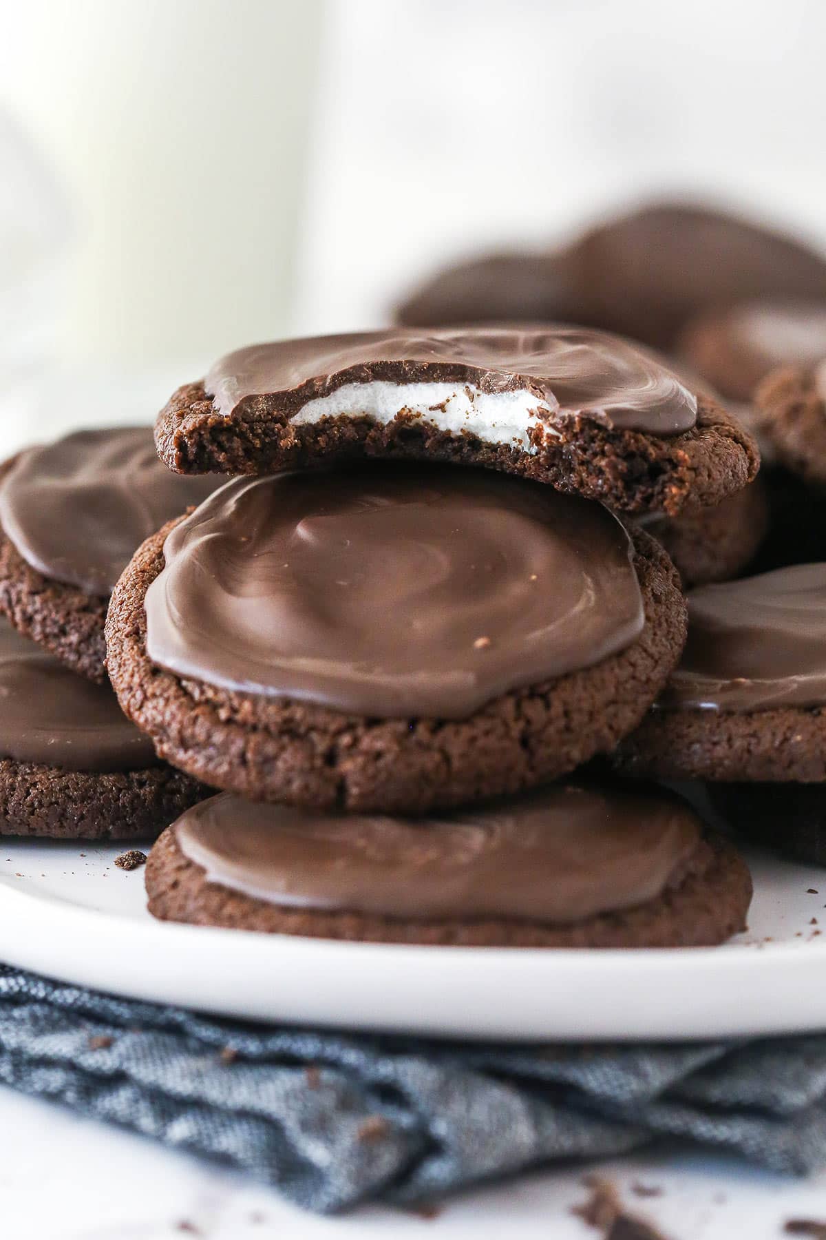 A plate of chocolate marshmallow cookies, one with a bite missing to show the marshmallow inside