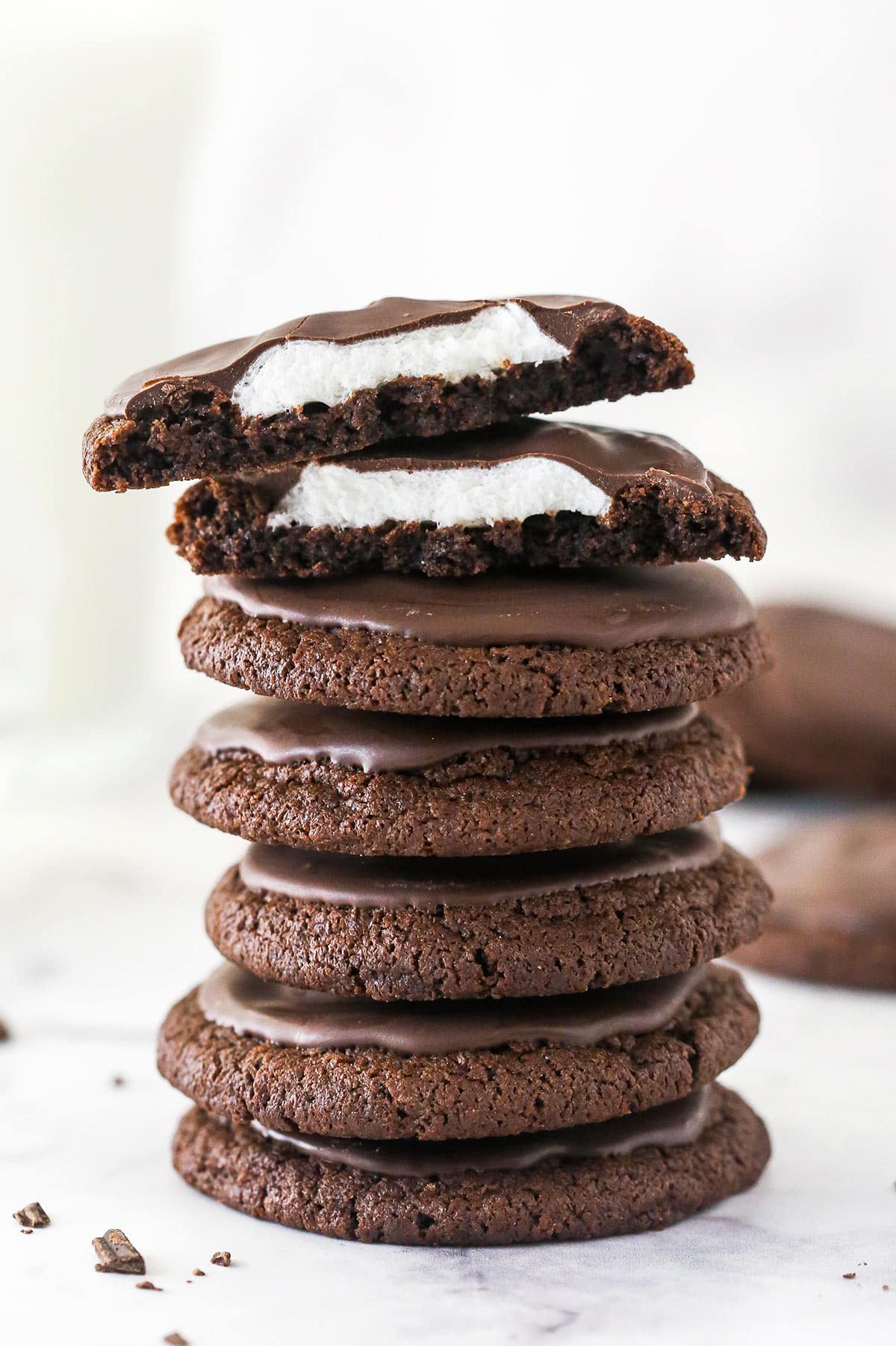 Chewy chocolate cookies are topped with a marshmallow and melted chocolate to make these irresistible Chocolate Marshmallow Cookies. A stack of chocolate marshmallow cookies, with one cut in top on half to show the marshmallow inside