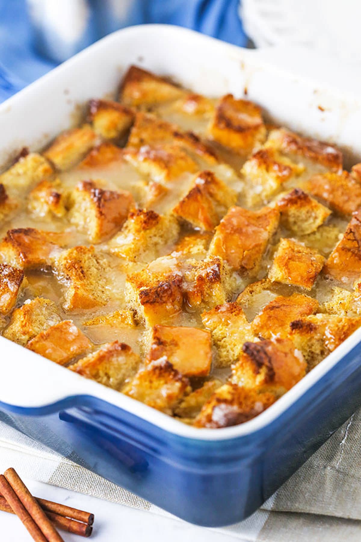 Old fashioned bread pudding just like grandma used to make! This easy recipe turns stale bread into a cozy pudding soaked in vanilla sauce. Freshly baked bread pudding in a pan next to two cinnamon sticks.