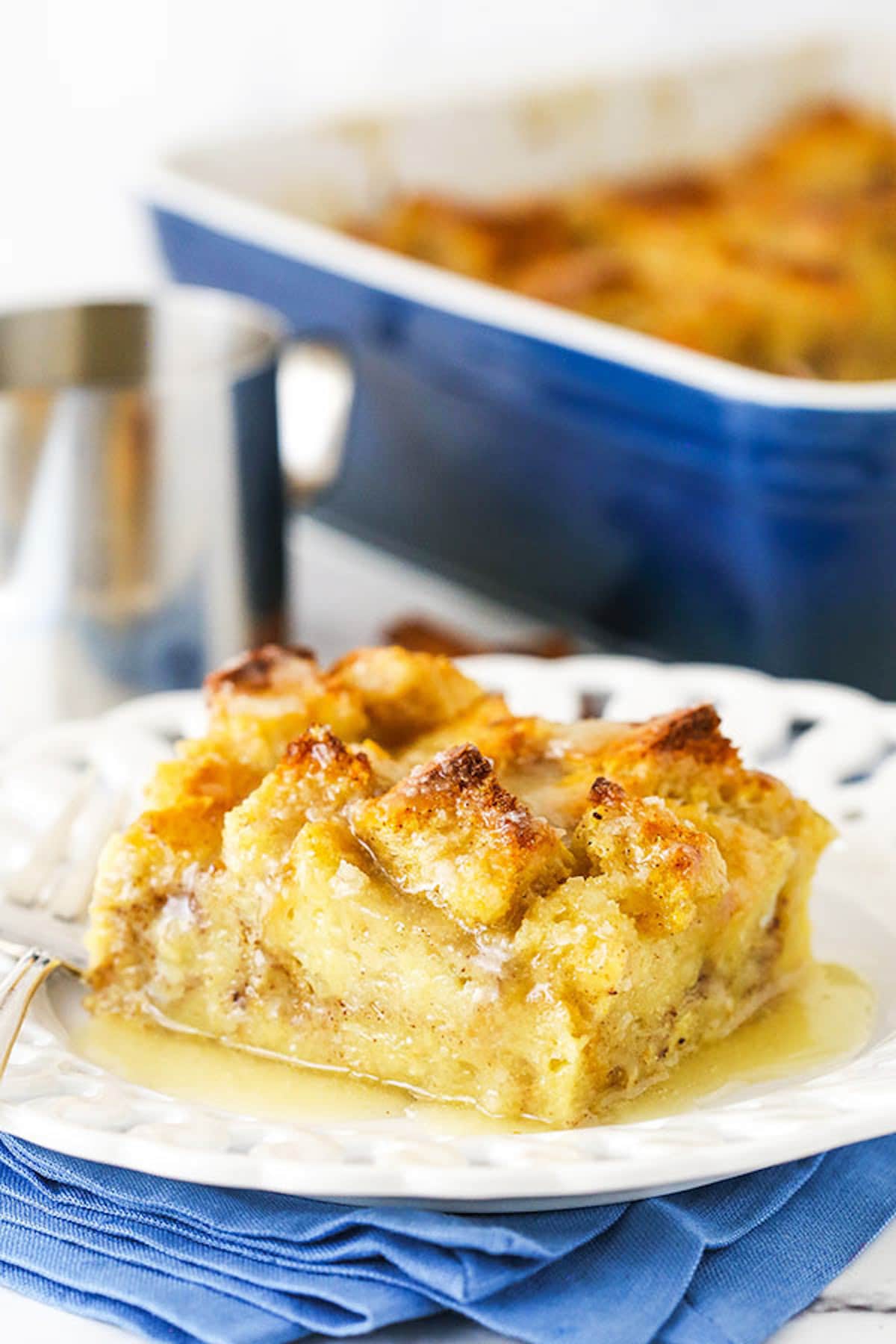 Old fashioned bread pudding just like grandma used to make! This easy recipe turns stale bread into a cozy pudding soaked in vanilla sauce. A square of bread pudding on a plate with the rest of the pudding in the background.