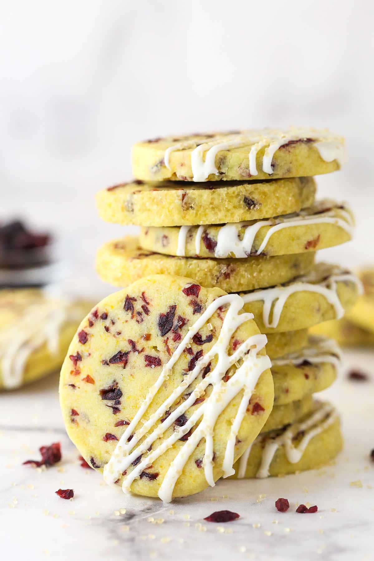Made with dried cranberries and orange zest, these Cranberry Orange Shortbread Cookies are tart and sweet with a bright citrus flavor. A stack of cranberry orange shortbread cookies, one leaning against the stack