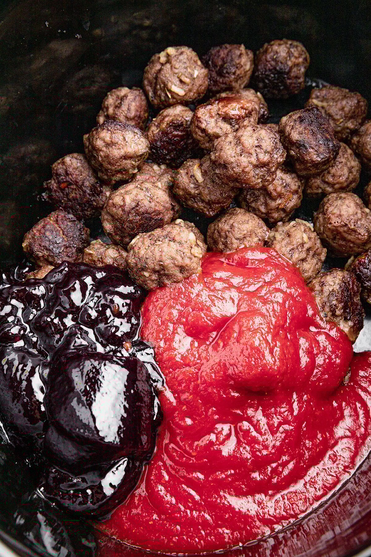 Pre-baked meatballs in a crock pot with chili sauce and grape jelly