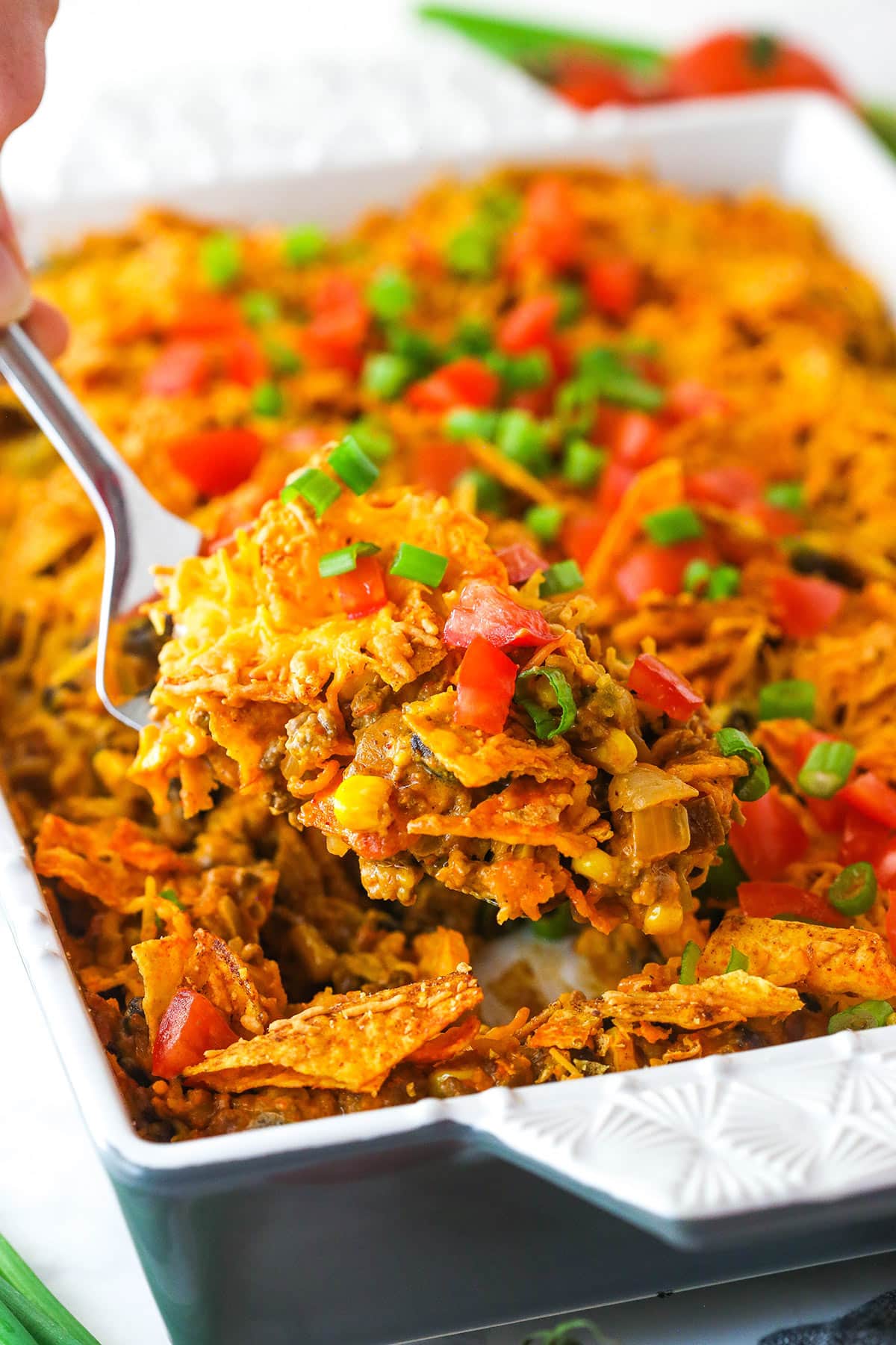 This Dorito casserole is made with layers of Doritos, ground beef, cheese, black beans, and corn and is packed with taco flavor. Taking a slice out of Dorito casserole.