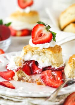 Strawberry shortcake on a plate with a couple of bites taken out of it.