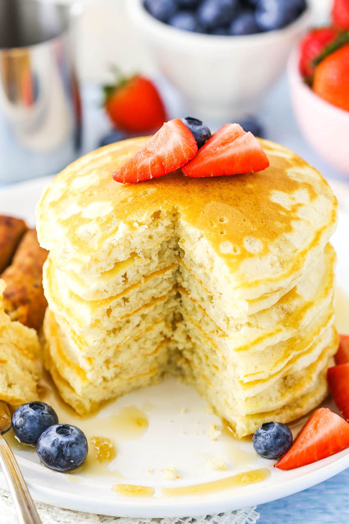 This easy recipe makes fluffy homemade pancakes that come together in less than 30 minutes. Pancakes stacked with a quarter removed on a white plate