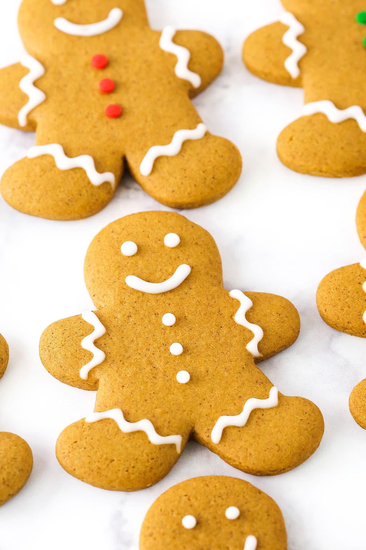 A gingerbread cookie decorated with white frosting on a white table.
