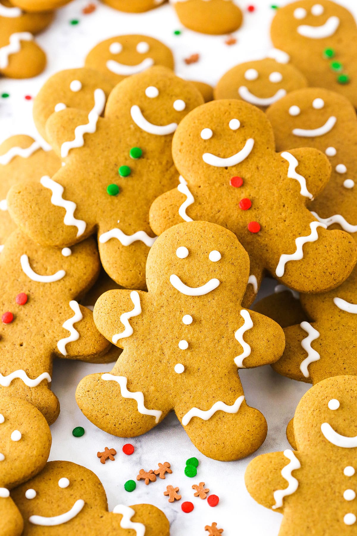 Gingerbread cookies in a pile, decorated with frosting and sprinkles.