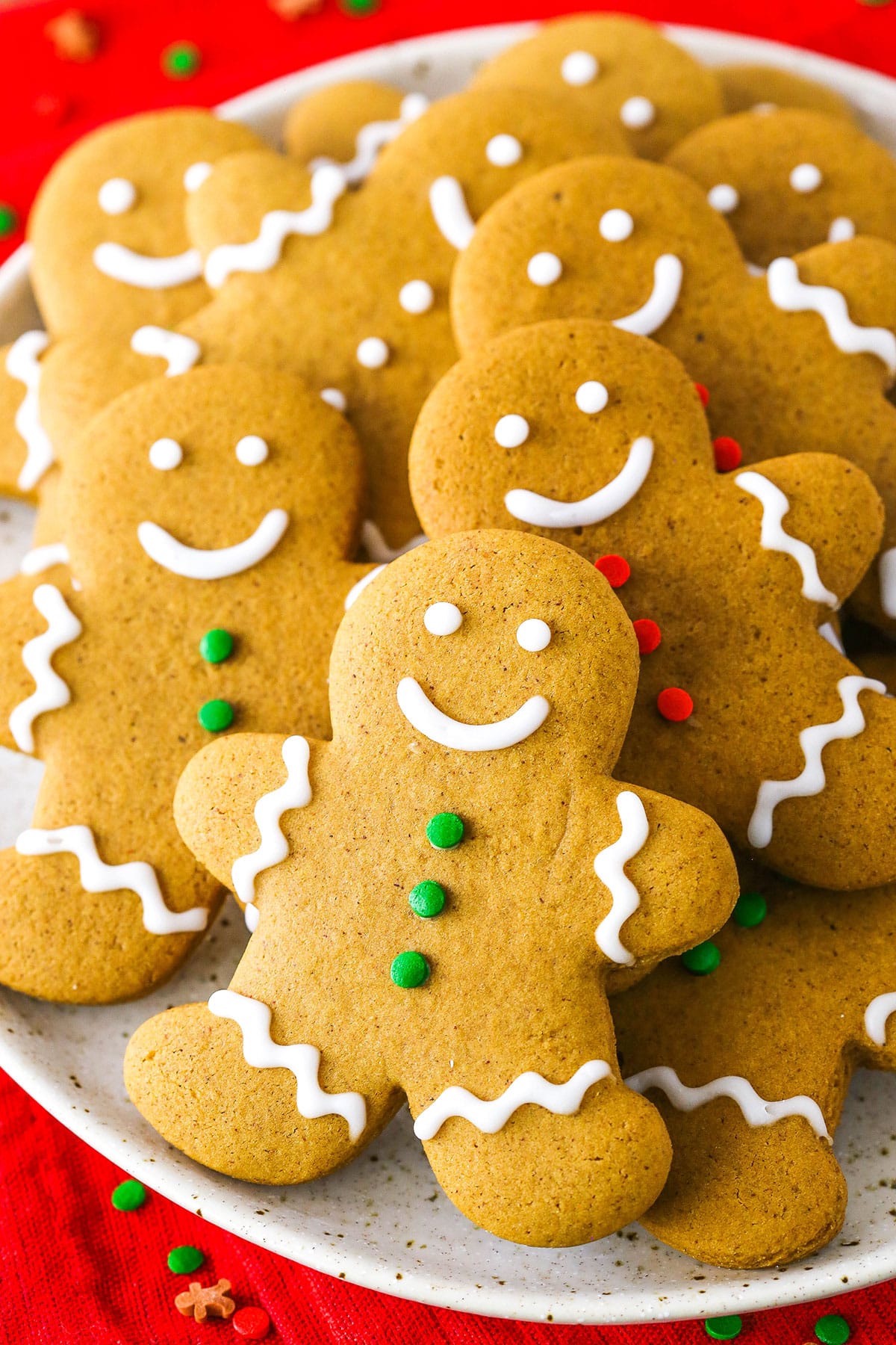 Gingerbread man cookies decorated with frosting layered on a white plate.