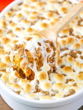 A scoop of Loaded Sweet Potatoes being taken with a wooden spoon