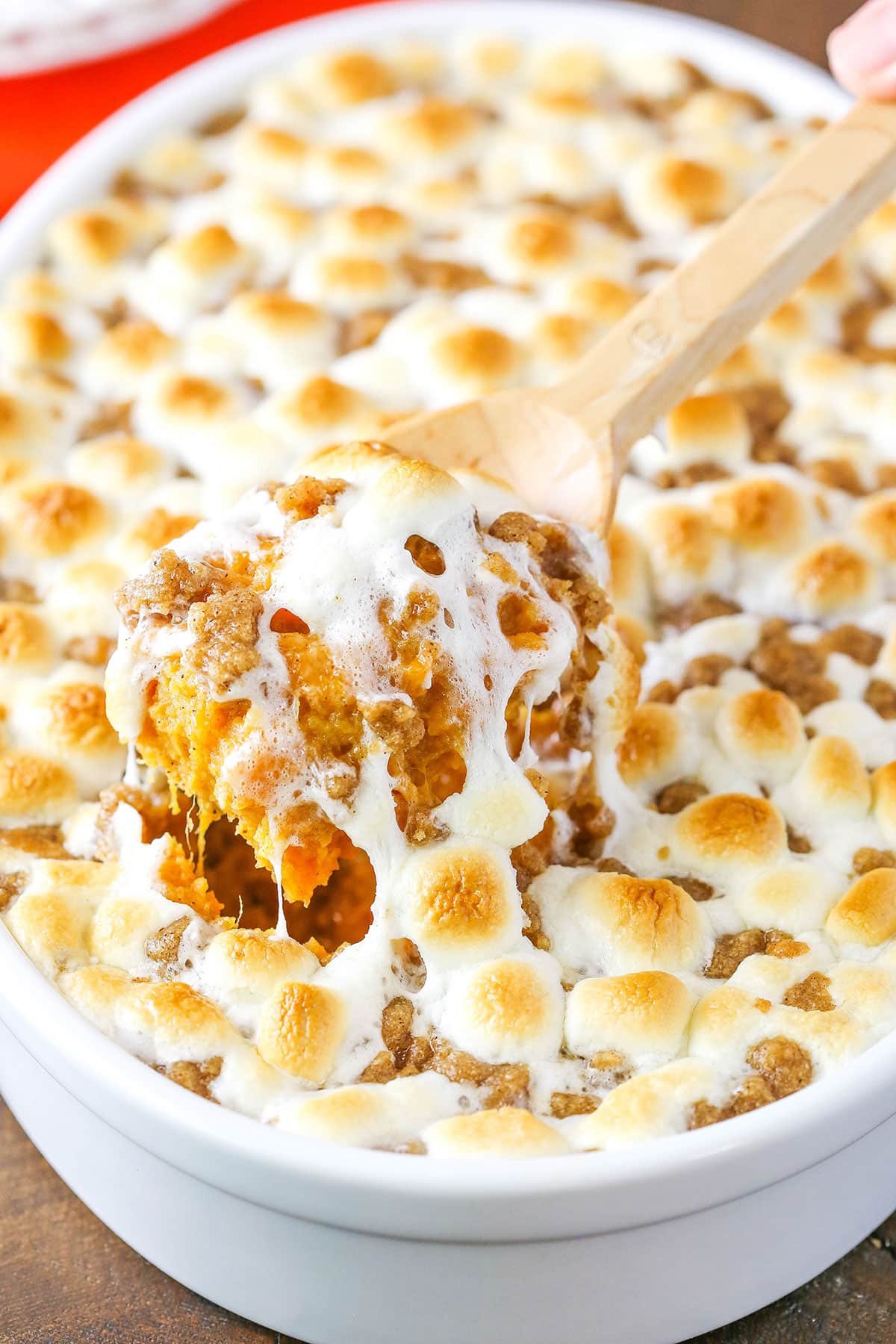 With fresh sweet potatoes, plenty of warm spices and a gooey marshmallow streusel topping, this is the best sweet potato casserole recipe! A scoop of Loaded Sweet Potatoes being taken with a wooden spoon