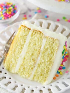 A slice of moist vanilla layer cake on a plate with a fork.
