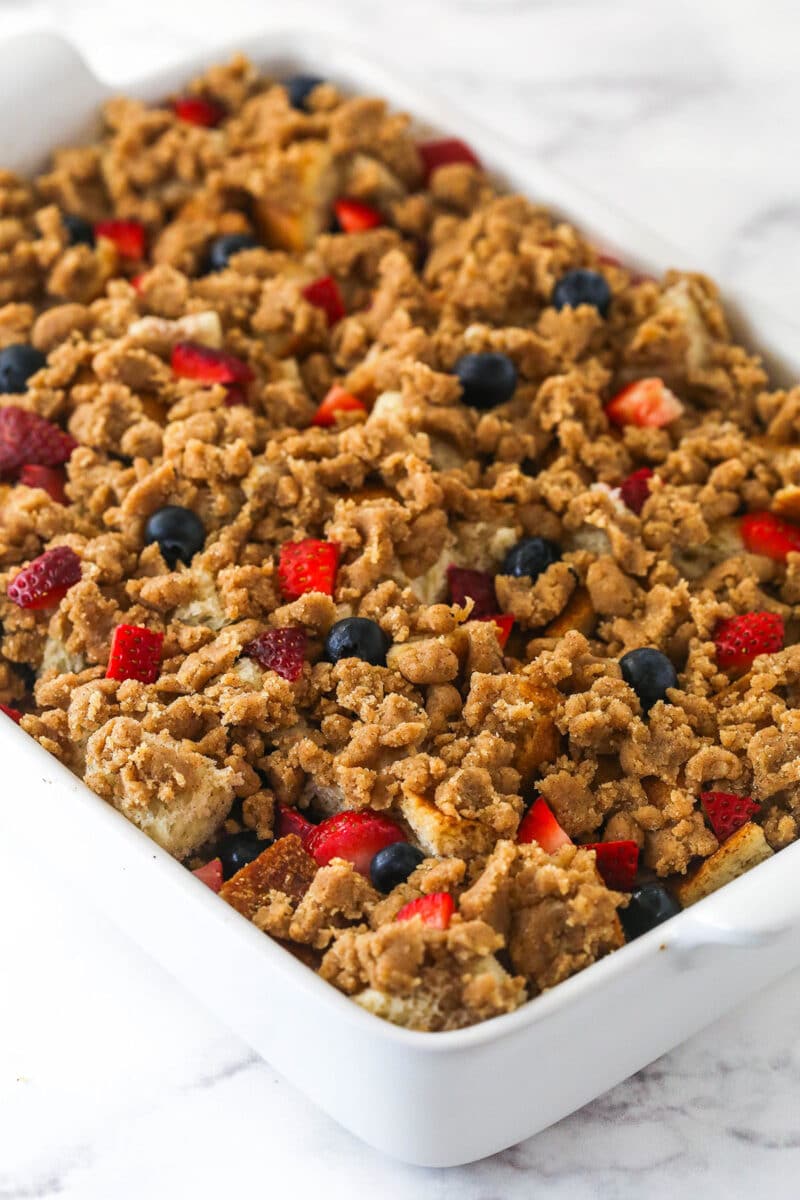 Sprinkling streusel topping over berry French toast casserole.