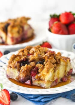A slice of berry French toast casserole served on a plate with maple syrup.
