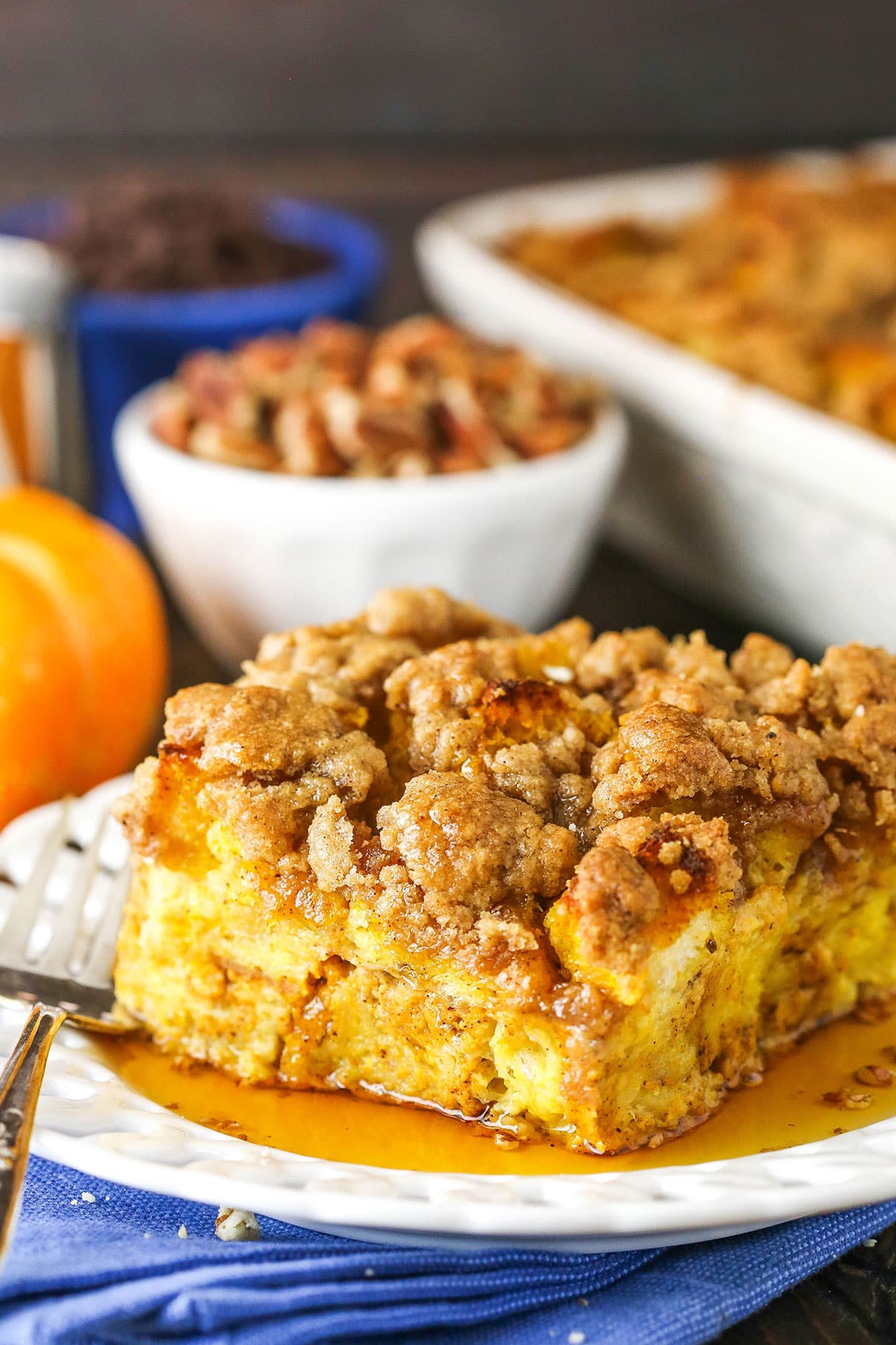 Side view of a square serving of Overnight Pumpkin French Toast Casserole on a white plate with a fork