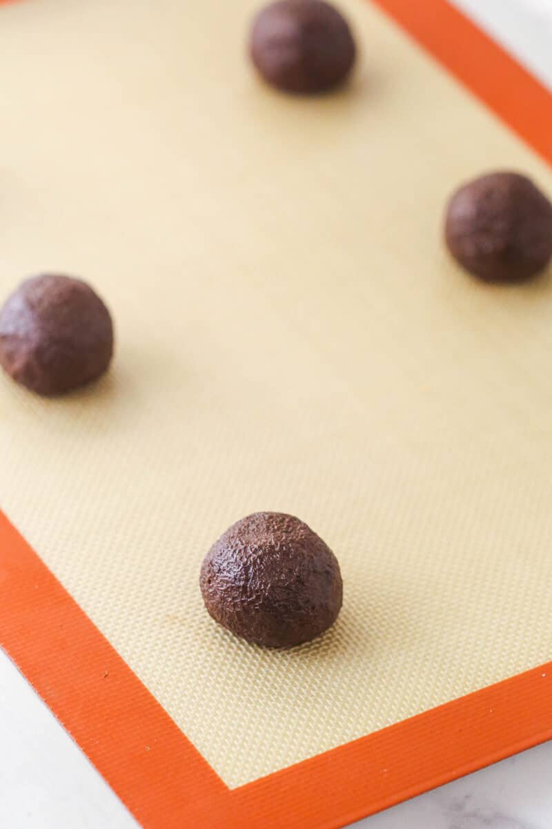 Chocolate cookie dough balls on a silicone mat.