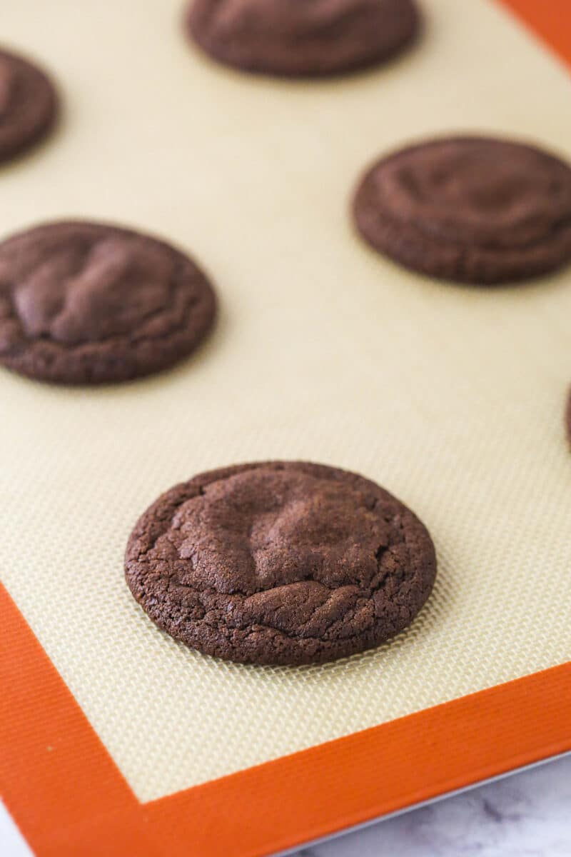 Baked chocolate cookies on a silicone mat.