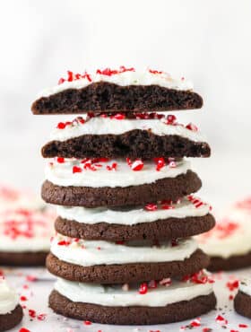A stack of Peppermint Frosted Chocolate Cookies with the top cookie cut in half to show texture.