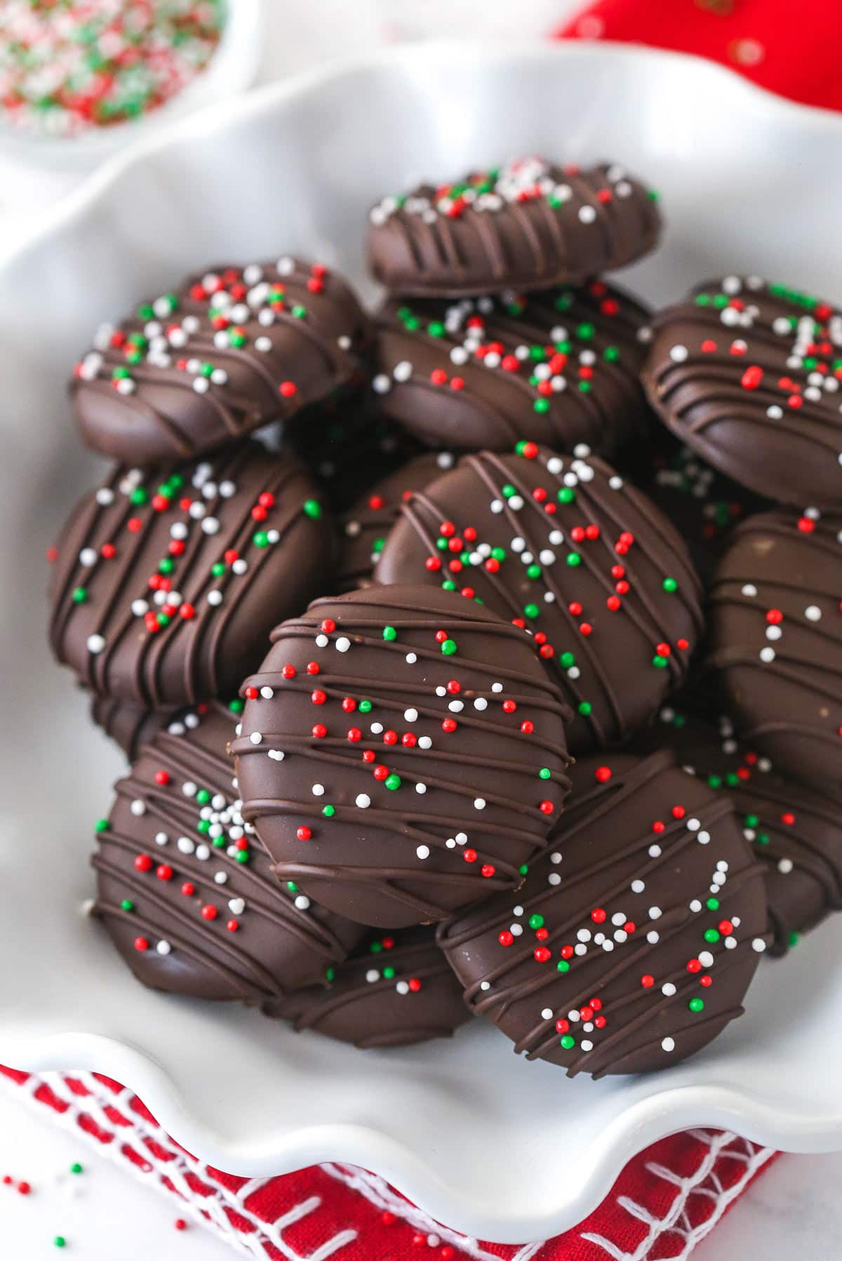 Peppermint patties are made up of a fondant-like peppermint filling wrapped in a delicate layer of chocolate and colorful sprinkles. Peppermint patties in a bowl.