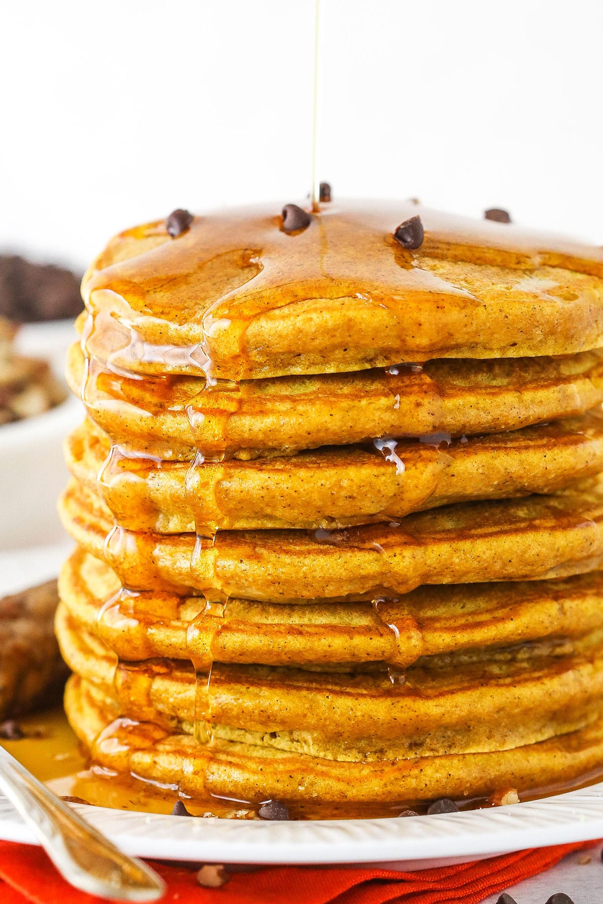 These soft, fluffy pumpkin pancakes are a comforting fall breakfast that everyone will love! They're easy to make and full of pumpkin flavor. Seven super fluffy pumpkin pancakes stacked on a plate.