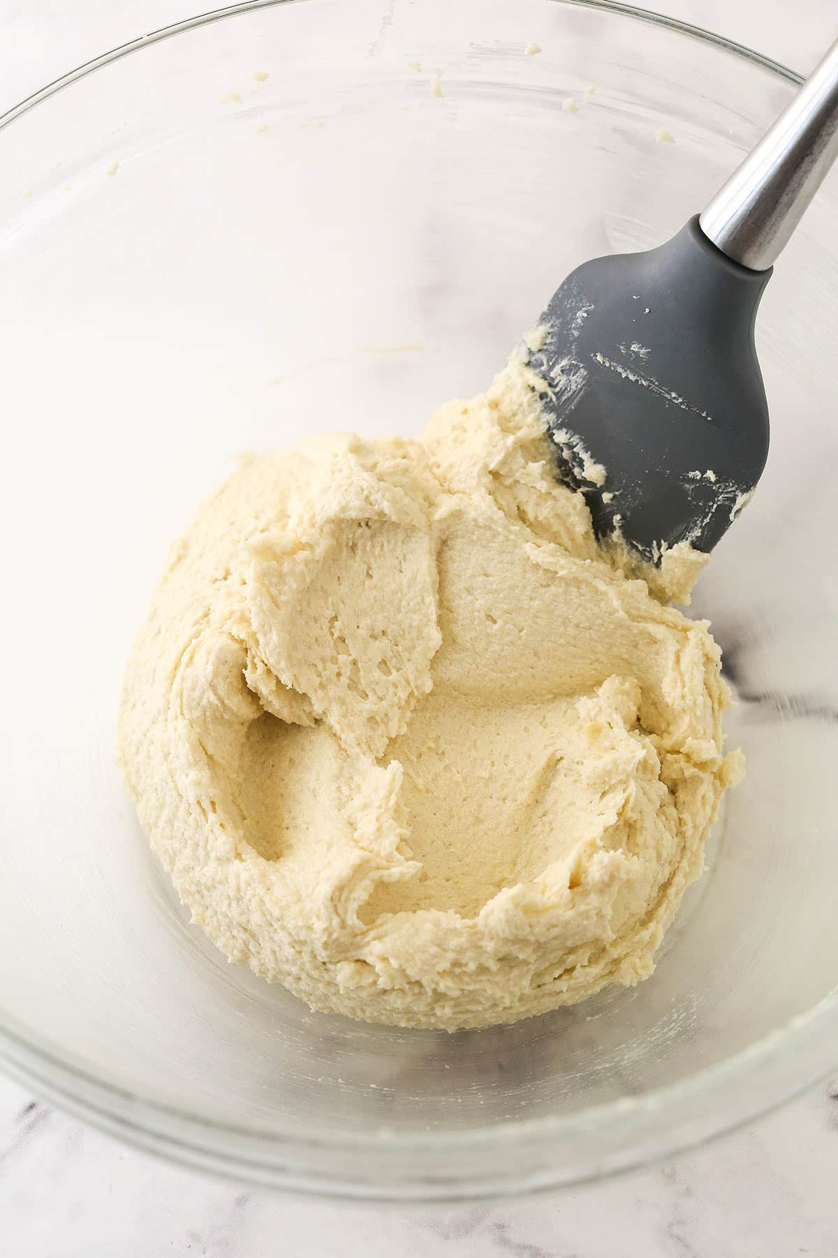 Creaming the butter and sugars in a glass bowl with a spatula.
