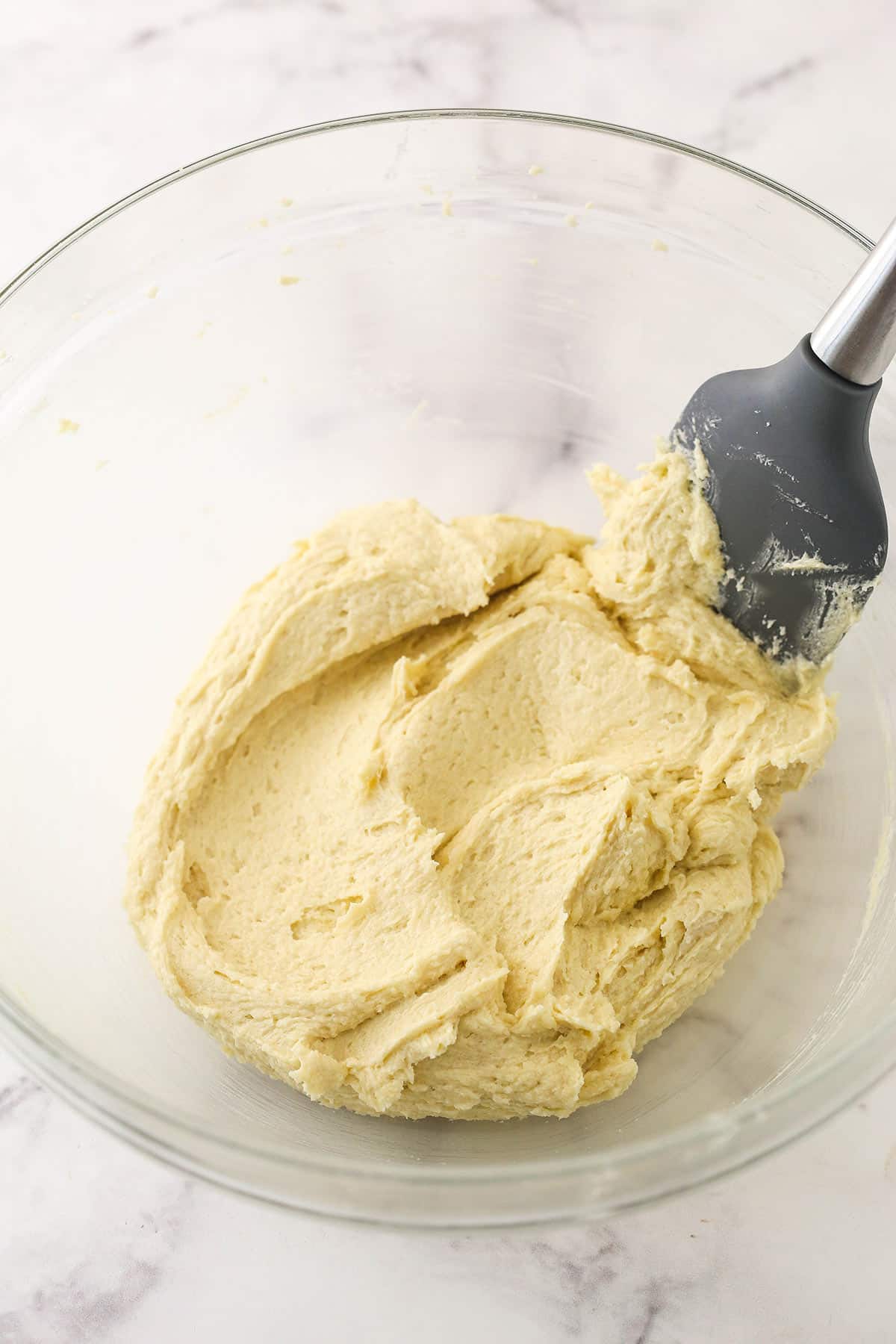 Creamed butter with egg and vanilla extract in a glass bowl.