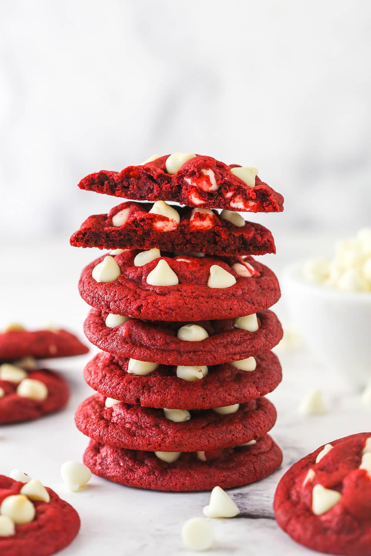 A tall stack of red velvet cookies with white chocolate chips on a countertop.