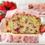 Strawberry bread on a serving platter with a slice cut out of it.