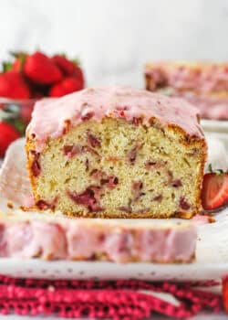Strawberry bread on a serving platter with a slice cut out of it.