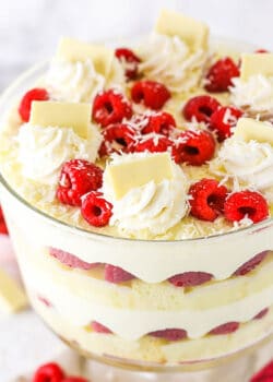 White chocolate raspberry trifle topped with swirls of whipped cream, fresh raspberries, and chocolate shavings.