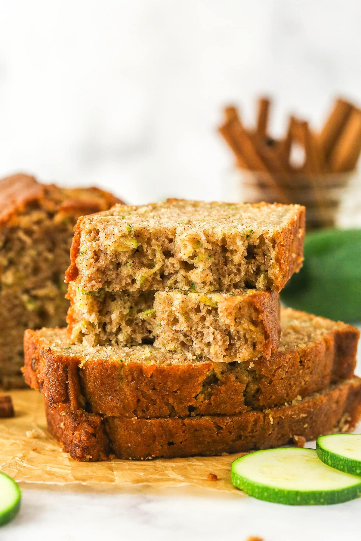 When life gives you zucchini, make this zucchini bread! It's so moist, the perfect amount of sweet, and has a subtle hint of cinnamon to it. Sliced of zucchini bread stacked on top of each other. The top slice is torn in half.